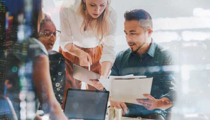 Marketing runs smoothly 1 | tycoonstory media Business team collaborating in a modern office, analyzing documents and data, symbolizing the real-world application of ai automation in enterprise workflows.