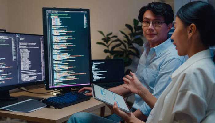 Coding interview platforms Software developers reviewing code on multiple screens during a technical assessment, demonstrating real use of coding interview platforms.