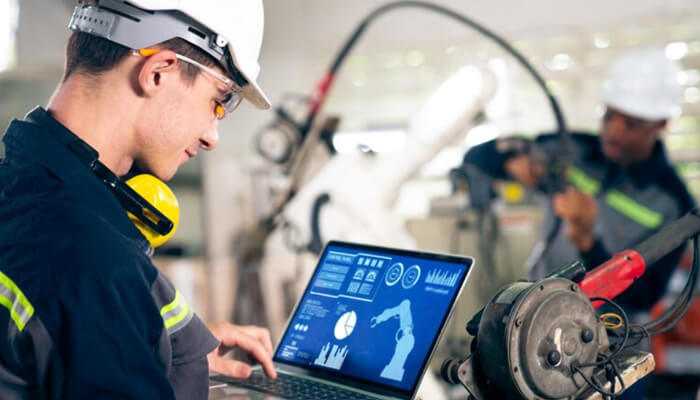 Predictive maintenance | tycoonstory media Technician monitoring maintenance time on a laptop during real-time equipment analysis in an industrial maintenance process.