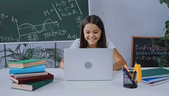 Strengths of uplarn - tycoonstory | tycoonstory media Uplarn. Com: a smiling student working on a laptop in a study environment, surrounded by books and stationery, with a blackboard full of mathematical equations in the background.