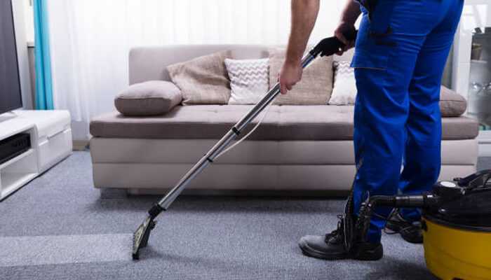 Technology meets tradition 1 | tycoonstory media A home services industry professional using a carpet cleaning machine to deep clean a living room carpet near a beige sofa.