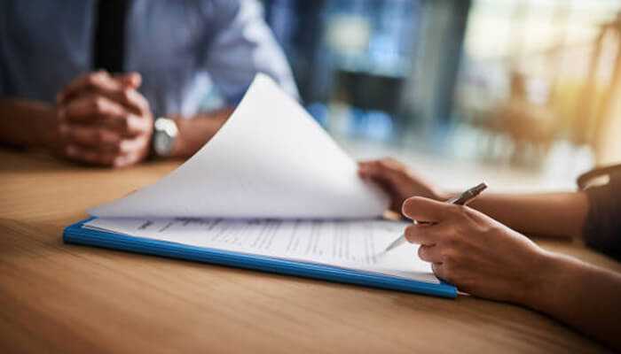 Term plans with riders | tycoonstory media Customer signing documents for term insurance plans during a consultation at an office table.