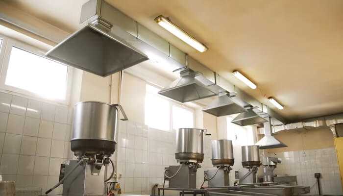 The right role of extractor hoods 1 | tycoonstory media Industrial dust extractors and ventilation hoods installed in a food processing facility to ensure clean air and safe working conditions.