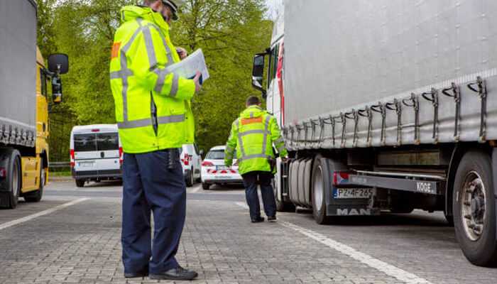 What the law says | tycoonstory media Trucking laws being enforced by safety inspectors, with officers checking trucks during a roadside inspection for compliance.
