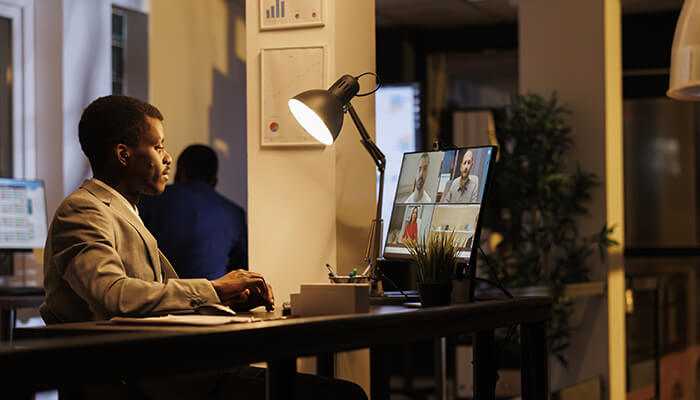 Work from anywhere 1 | tycoonstory media A man in a suit working remotely, attending a virtual meeting, with a virtual office address sydney on his screen.
