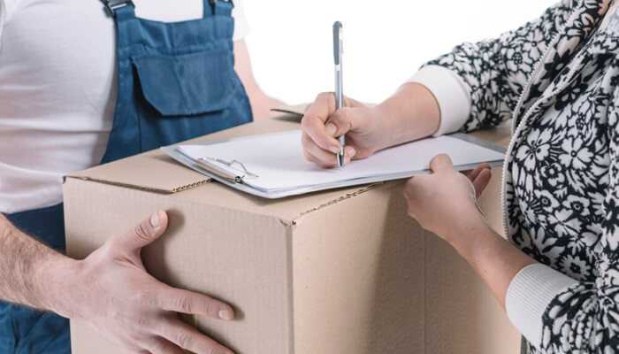 Common reasons for late parcel delivery after pre-shipment | tycoonstory media Customer signing delivery receipt during preshipment process with courier holding a package