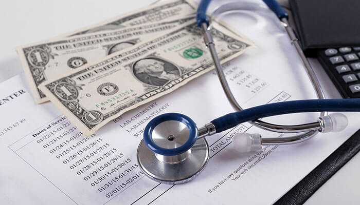 Look at co-payments and sub-limits - tycoonstory | tycoonstory media Cost of medical insurance in india illustrated with stethoscope, currency notes, medical bills, and calculator on a desk.