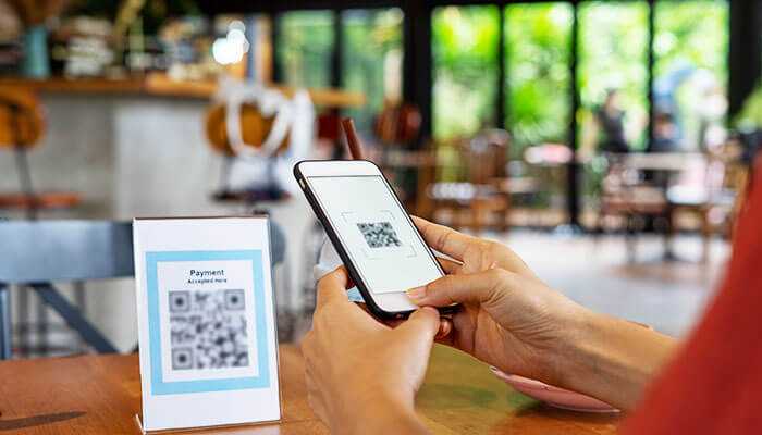 Pairing offline sightings with digital follow-ups - tycoonstory | tycoonstory media Customer scanning a qr code with smartphone in a café, showing creative marketing moves through qr engagement and offline-to-digital connection.