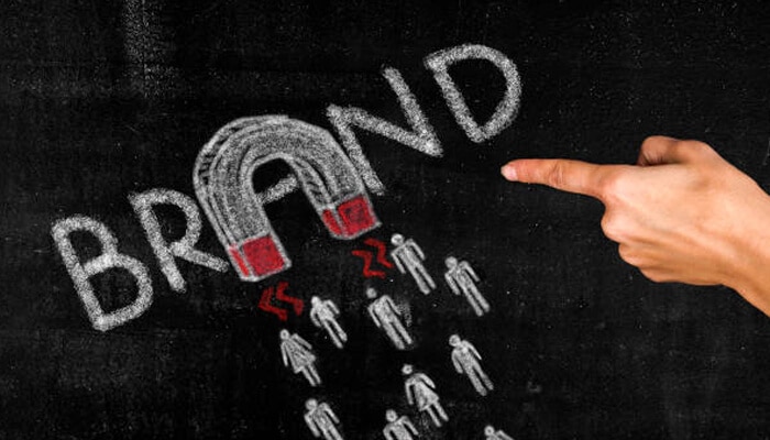 Brand Hand pointing at chalkboard illustration of a brand attracting people with a magnet symbol.