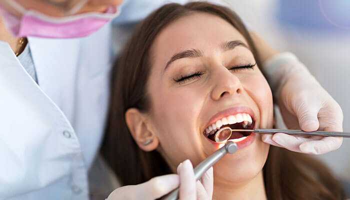 Visit your dentist regularly - tycoonstory | tycoonstory media Dentist performing a checkup on a patient, highlighting a healthy smile.