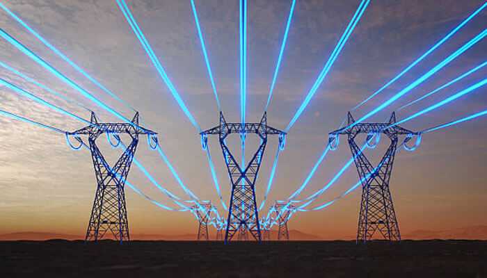 Industrial applications powering smart manufacturing - tycoonstory | tycoonstory media Power distribution lines with glowing blue energy beams across transmission towers, symbolizing advanced grid technology and smart energy systems.