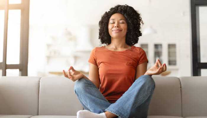 Neurological health A woman meditating on a couch, promoting mental relaxation and stress reduction, essential for maintaining neurological health.