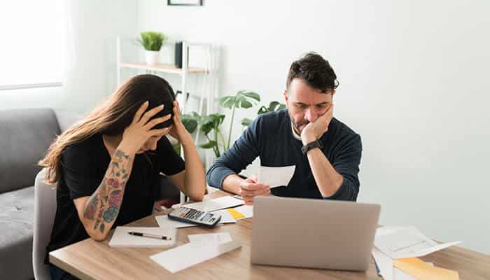 Why communication matters more than balance sheets - tycoonstory | tycoonstory media Stressed couple reviewing bills and paperwork, highlighting the strain financial infidelity places on trust and communication.