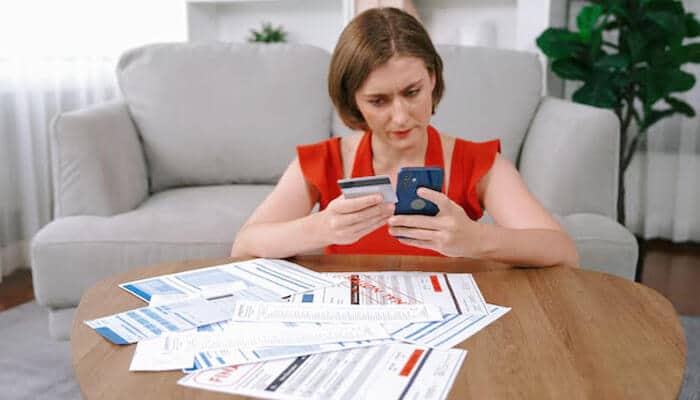 Avoid multiple loan applications at once - tycoonstory | tycoonstory media A woman comparing credit card statements and managing expenses at home, representing financial stress relief and debt management through a personal loan for salaried professionals.
