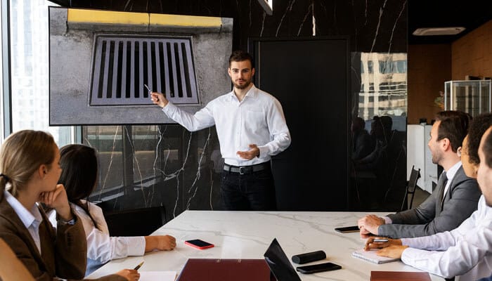 Building a culture of curiosity and collaboration - tycoonstory | tycoonstory media Engineer giving a presentation on stormwater management strategies using drainage system visuals during a team meeting.