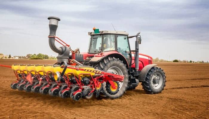 Disc plough or mb plough - tycoonstory | tycoonstory media Modern red tractor with seed drill tractor implements preparing soil for sowing.
