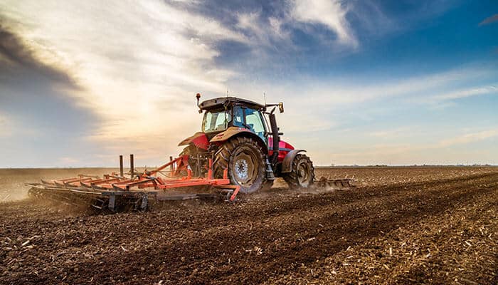 Get more from every pass - tycoonstory | tycoonstory media Tractor pulling soil tillage tractor implements to prepare farmland under a bright sky.
