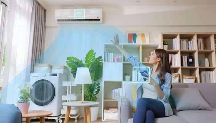 Improved indoor air quality - tycoonstory | tycoonstory media Woman using a smart air conditioning unit inside a modern living space, illustrating comfort and energy efficiency powered by a commercial hvac system.