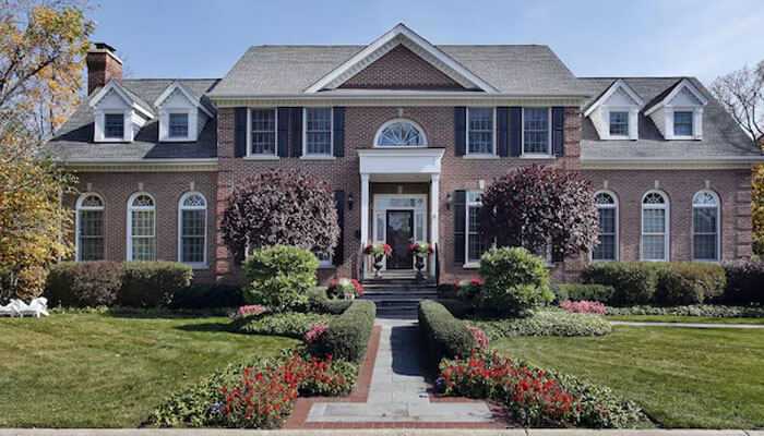 Make your as-is listing stand out - tycoonstory | tycoonstory media Elegant two-story brick house with landscaped front yard, showcasing curb appeal and classic design — ideal example of as-is austin homes.