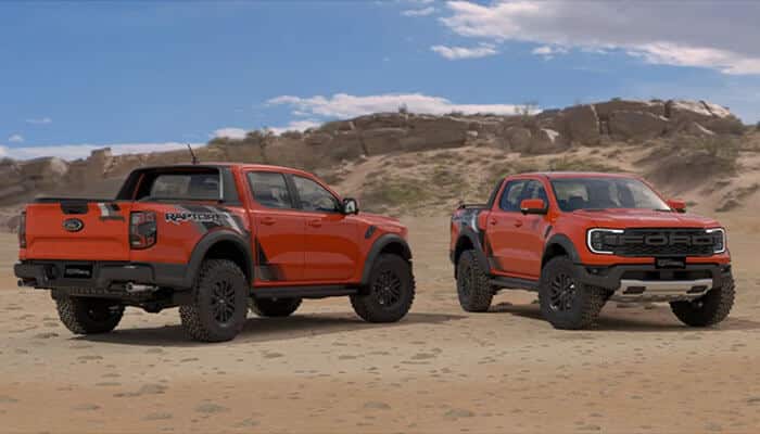 Off-road performance features - tycoonstory | tycoonstory media Two ford ranger raptors in bright orange displayed on rocky terrain, highlighting the truck’s aggressive styling and adventure-ready stance.