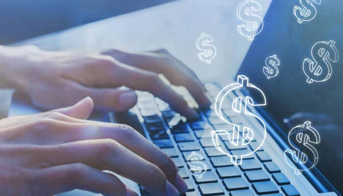 Second income stream Close-up of hands typing on a laptop keyboard with floating dollar symbols, representing online opportunities for creating a second income stream.