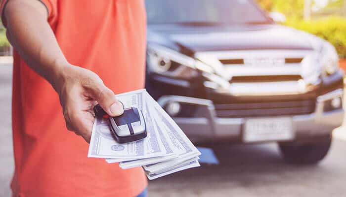 Used car valuation One person's hand in a white shirt handing a car key to another person, symbolizing a transfer of ownership after a Used Car Valuation and purchase.