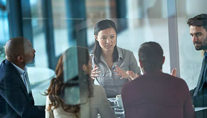 Protect your business model A diverse team of professionals engaged in a serious discussion around a conference table, collaborating on strategies to protect your business model and ensure sustainable growth.