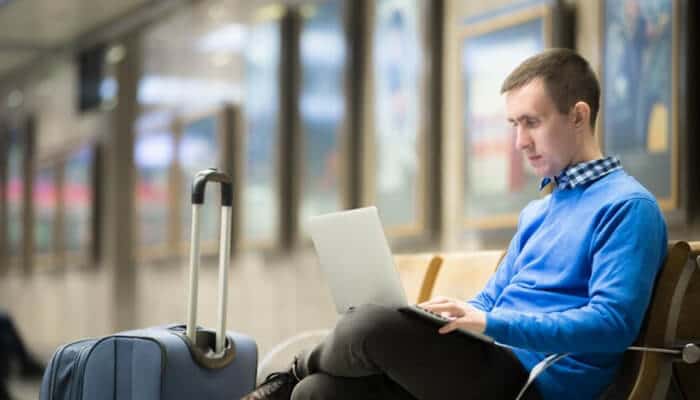 Key features to look for in a travel insurance plan for germany 1 | tycoonstory media Traveler at an airport using a laptop to manage travel insurance plans, review policy details, and prepare for a safe journey.