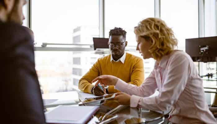 Global employment laws A group of professionals sitting around a glass table in a modern office, discussing documents and policies that could relate to navigating global employment laws.