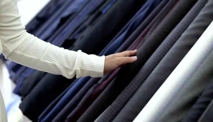 Uniform manufacturer A person inspecting a variety of neatly arranged fabric rolls, illustrating the material selection process when working with a uniform manufacturer.