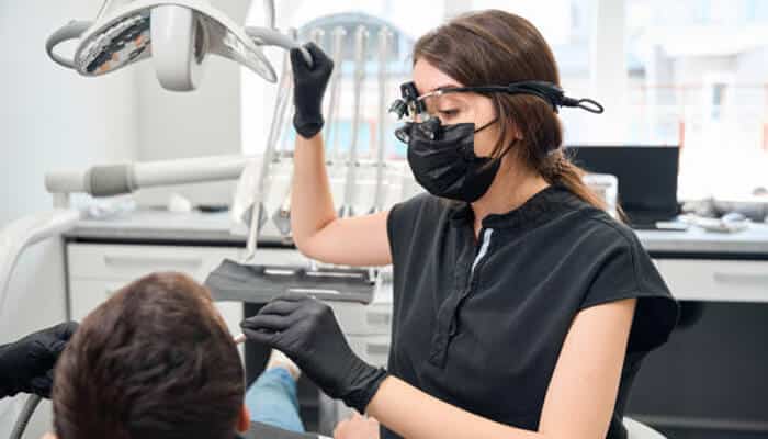 How better optics improved workflow | tycoonstory media Dentist using dental loupes while performing a dental procedure on a patient in a modern dental clinic