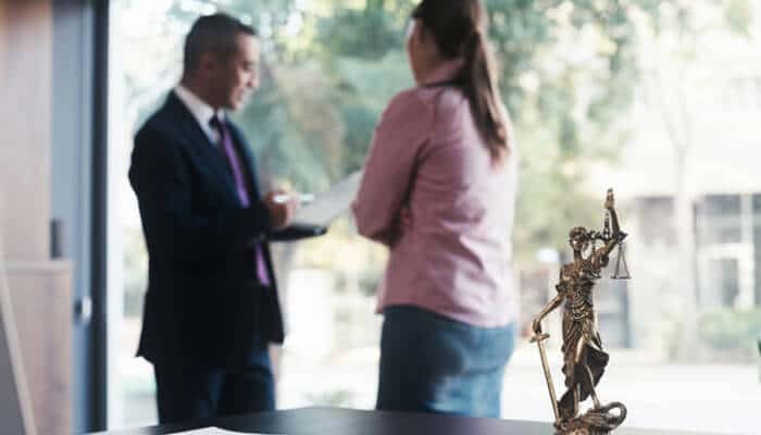 How to collect reliable witness statements | tycoonstory media An attorney consulting with a client in an office setting, with a statue of lady justice visible on the desk, symbolizing the importance of fair legal representation in driving accident claims.