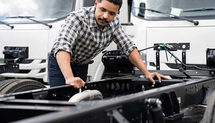 Evaluate frame construction and materials | tycoonstory media A person inspecting the frame of a trailer, evaluating its construction materials and components, an essential step when shopping for a trailer to ensure durability and performance.