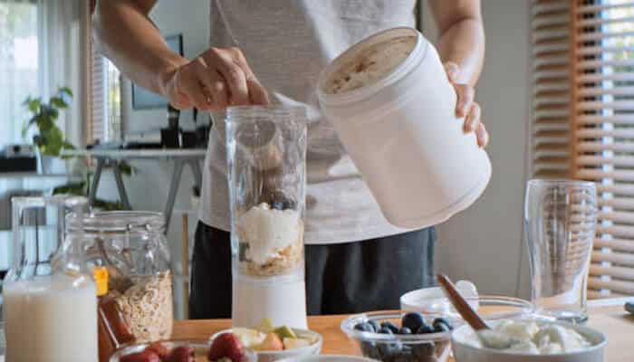 Protein shakes for weight loss | tycoonstory media A person preparing a smoothie with protein powder, fruits, and yogurt, demonstrating a nutritious and tasty best protein shake for post-workout recovery.