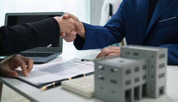 Start the career | tycoonstory media Two professionals shaking hands over a real estate contract, representing opportunities in the real estate industry.