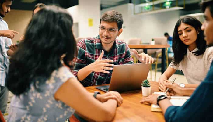 Employees are financially and emotionally Team of colleagues collaborating around a laptop in a modern office, discussing ideas and strategies, showing how employees are financially and emotionally supported through teamwork and engagement