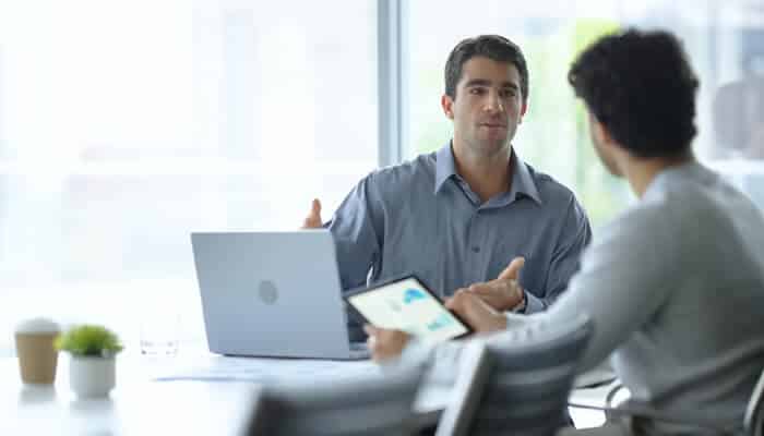 Web design services for small business growth and scalability | tycoonstory media Two professionals having a discussion in a modern office setting, emphasizing the importance of choosing professional web design services for business growth and scalability.