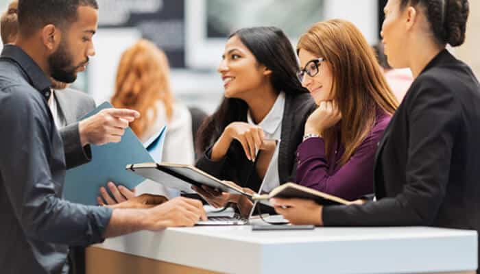 25 | tycoonstory media Professionals networking and discussing ideas at a booth during hr conferences, sharing notes and insights on workplace trends and talent management.