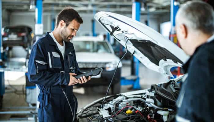 Airflow and coolant flow remove excess heat | tycoonstory media A mechanic using diagnostic tools to assess an engine, ensuring proper heat control through effective airflow and coolant flow to maintain optimal performance.