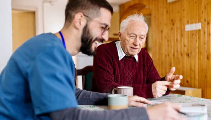 Companionship and emotional support | tycoonstory media A caregiver providing companionship and emotional support to an elderly person during a conversation over coffee, highlighting the importance of in-home care services for seniors.