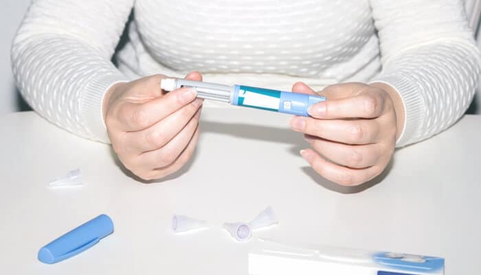 Do you get any benefits when taking ozempic for weight loss | tycoonstory media A person holding an injection pen and preparing a dose while learning whether ozempic safe for weight loss is an option under medical guidance.