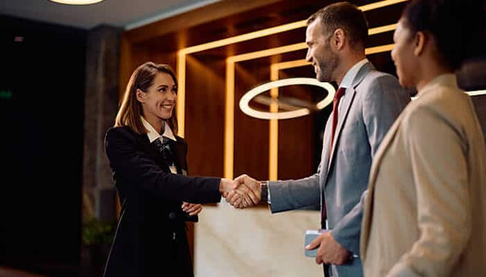 Empower your team | tycoonstory media Hotel staff warmly greeting guests at reception, creating a seamless hospitality experience through professional service and welcoming interaction.