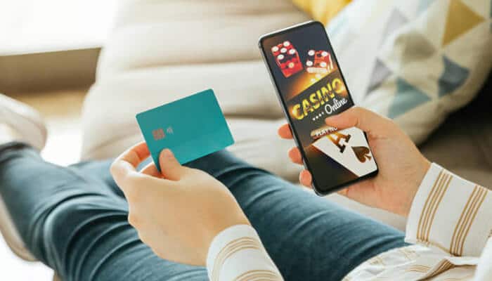 Flexible and localized payment options | tycoonstory media A person using a credit card and smartphone to play online casino games. 96ace offers flexible and localized payment options, making it easy for players to enjoy their favorite games securely.