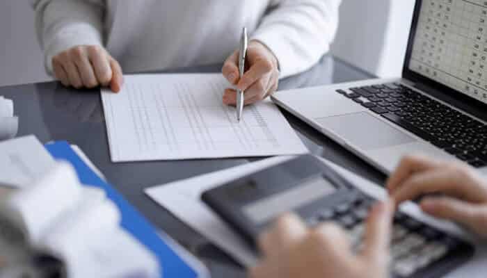 How inquiry management supports funding success | tycoonstory media Two people reviewing business documents and calculations, highlighting the role of business credit inquiries in funding success.