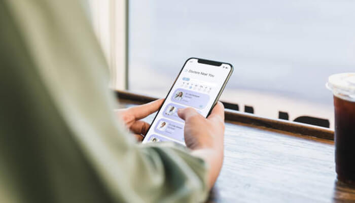 Ignoring mobile user behavior patterns | tycoonstory media A person browsing through a mobile app with a focus on finding a healthcare provider, showcasing the importance of user-friendly healthcare website design for seamless navigation.