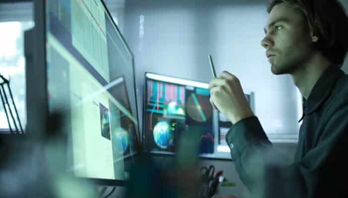 Investigate market position | tycoonstory media Business analyst reviewing market data on multiple screens to evaluate businesses for sale online and assess growth potential.