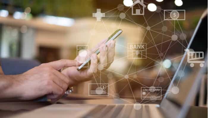 Partner with full-suite banking platforms | tycoonstory media A person using a smartphone with financial icons, illustrating how beyond the api, businesses can integrate embedded finance for better customer experience and efficiency.