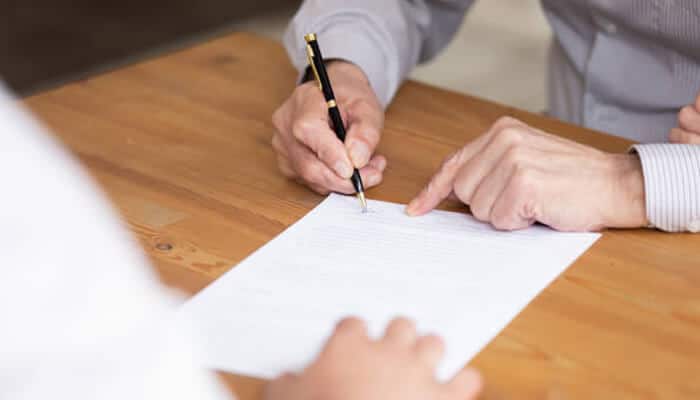 Policies that match work and contracts | tycoonstory media A business owner reviewing and signing policy documents as part of setting up comprehensive business insurance plans to manage risk and protect company operations.