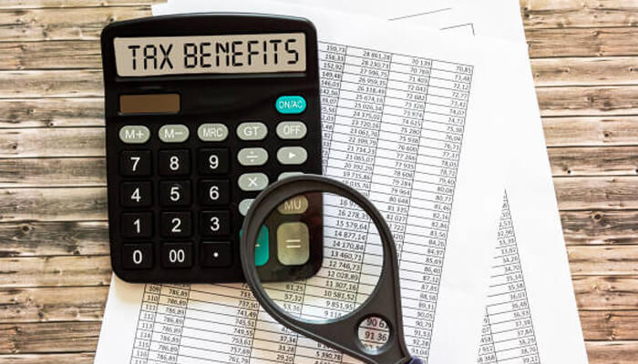 When tax benefits may not apply as expected | tycoonstory media Term insurance tax benefits - a calculator with'TAX BENEFITS' on its screen, accompanied by a magnifying glass, illustrating the detailed review of term insurance tax advantages.