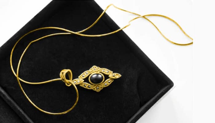 Why choose an obsidian pendant 1 | tycoonstory media Beautiful obsidian pendant displayed in a jewelry box. The gold necklace features an elegant design, with a striking obsidian stone at the center, perfect for any occasion.